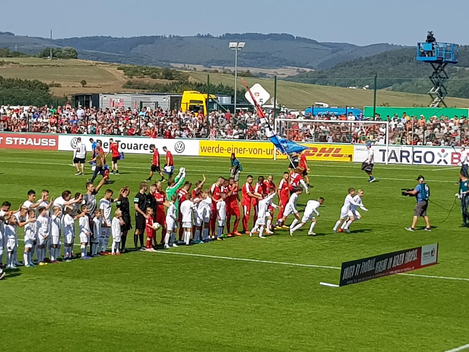 Teams line up on the pitch before a DFB-Pokal match with a full stand behind
