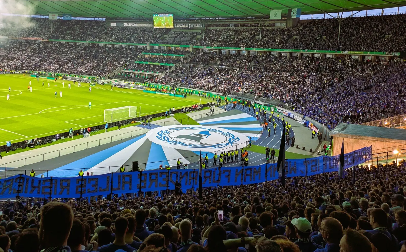 Fans with a large blue banner in the Berlin stadium at the 2025 DFB-Pokal final