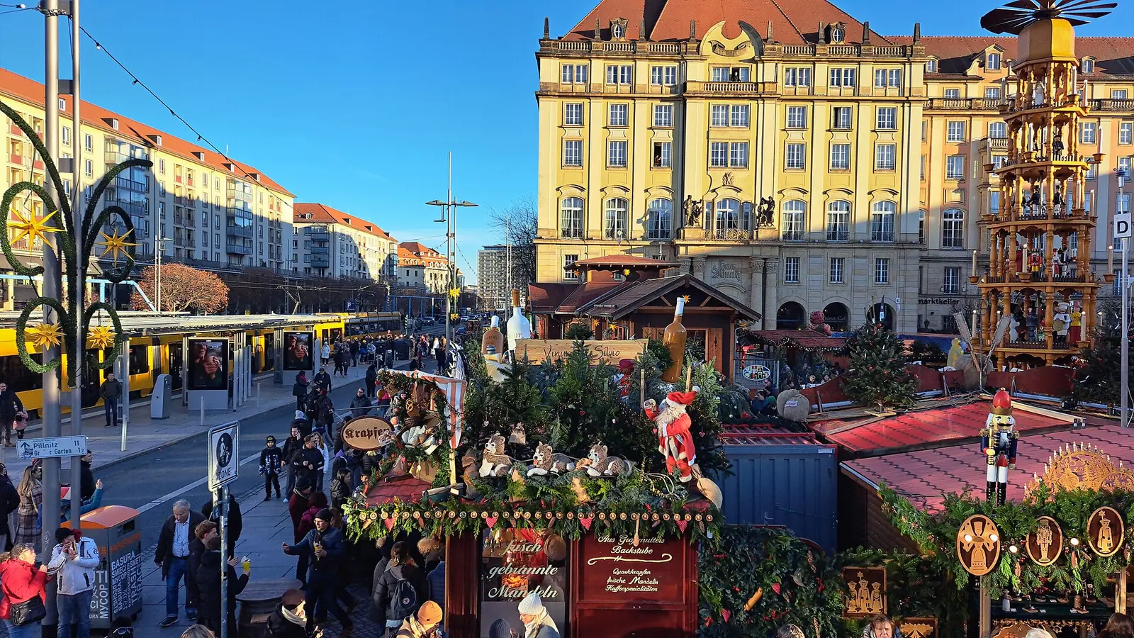 Visitors among wooden stalls at the 590th Striezelmarkt on the Altmarkt in Dresden under a blue sky