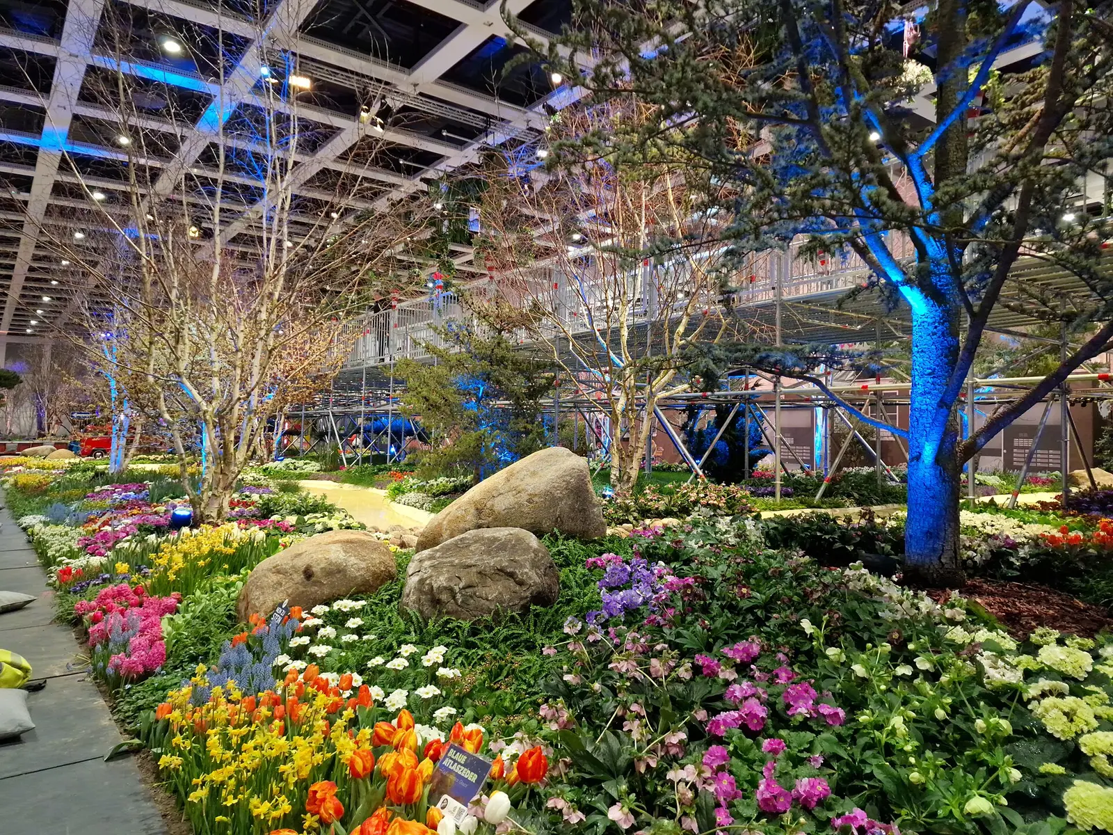 Flower and garden display with a blue-lit tree inside a hall at the International Green Week in Berlin