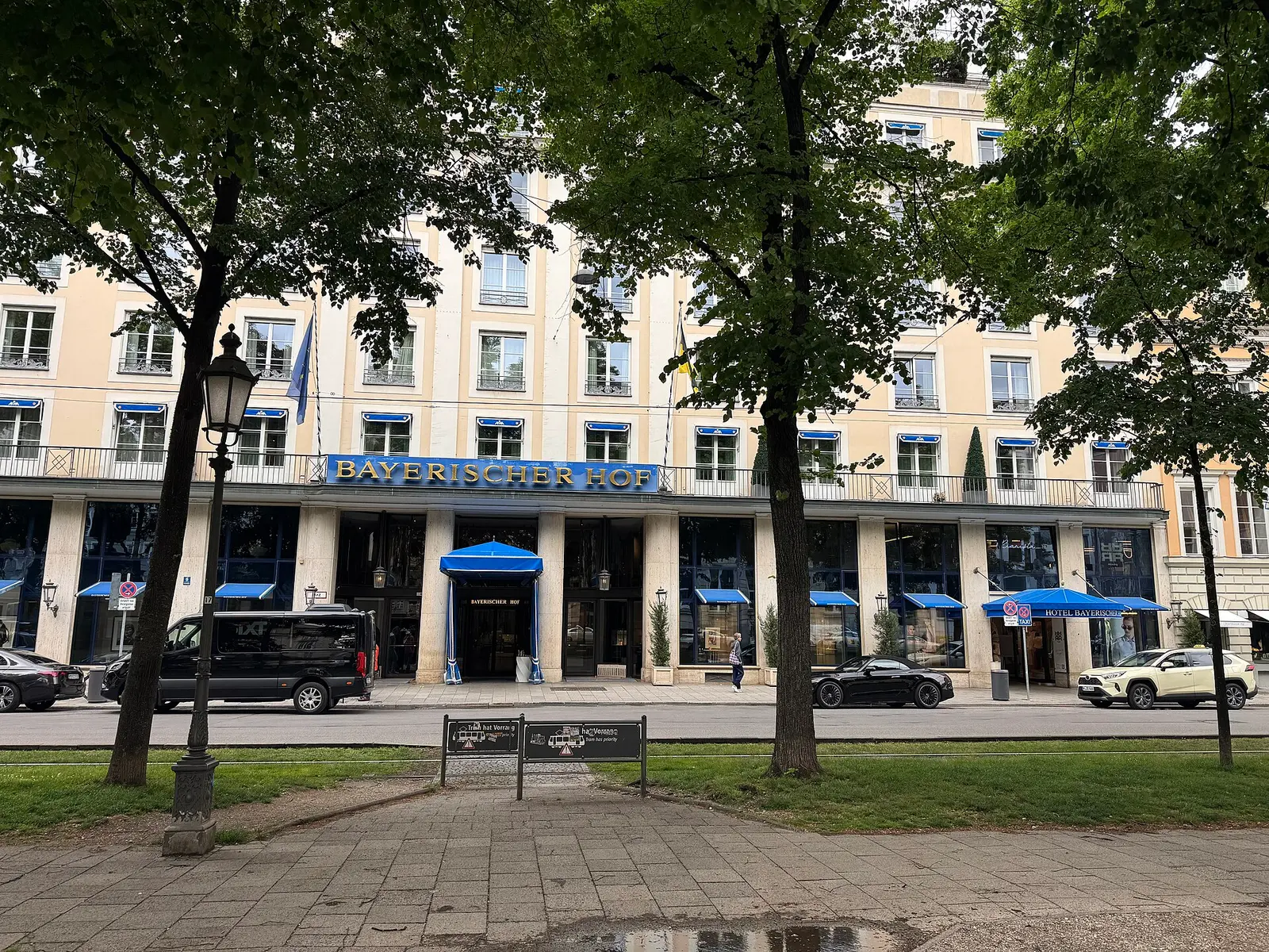 Front facade of the Hotel Bayerischer Hof on Promenadeplatz in Munich seen across a tree lined square