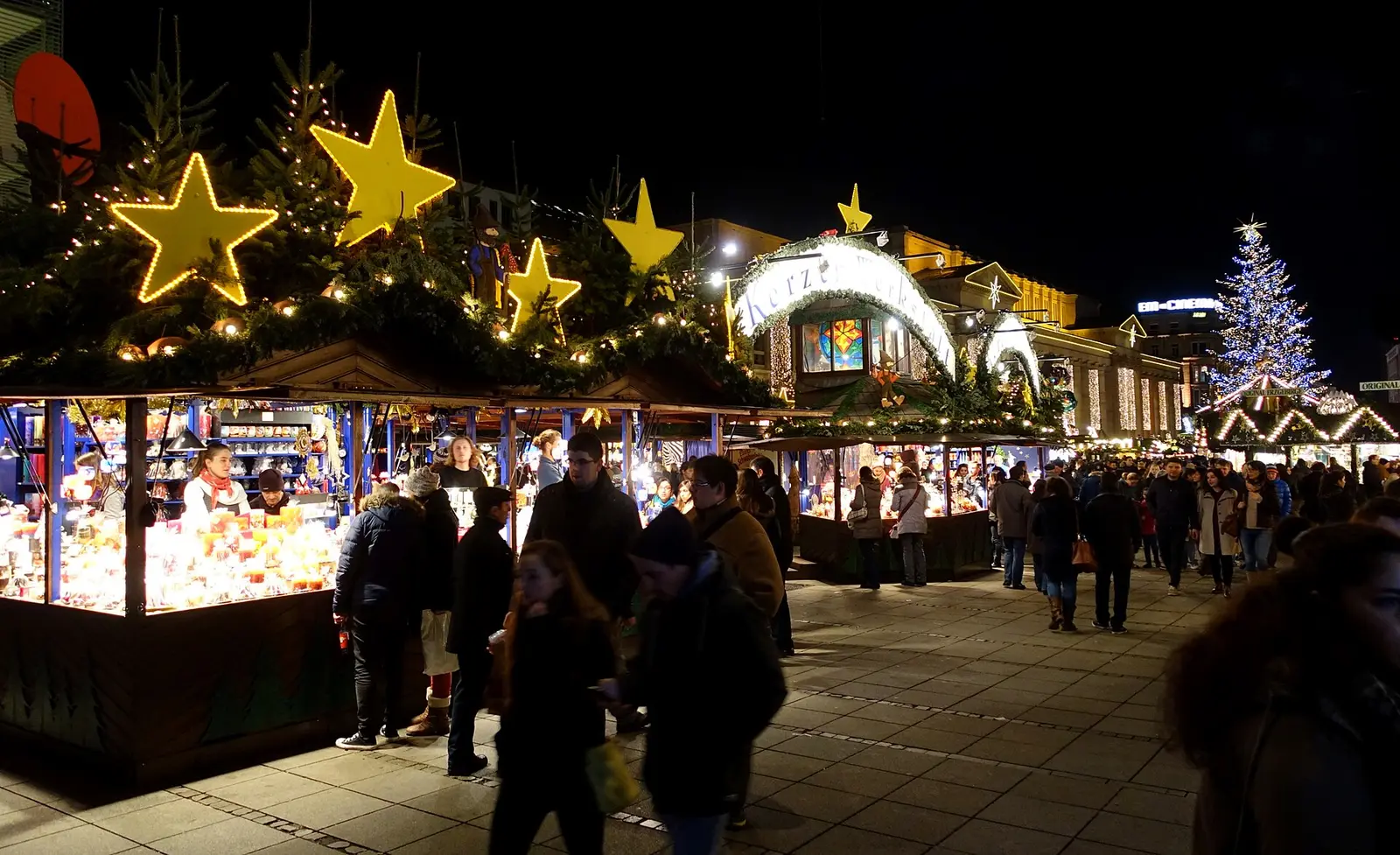 Crowds browse lit wooden stalls at the Stuttgart Christmas market at night